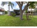 Spacious backyard with lush grass, large tree, and a unique hanging chair at 14914 Capri Ln, Hudson, FL 34667