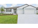 New construction home with light gray siding, two-car garage, and a well-manicured lawn at 14006 Ginnie Springs Way, Parrish, FL 34219