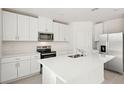 Modern kitchen featuring white cabinets, stainless steel appliances, and a large island at 144 Lazy Shore Dr, Nokomis, FL 34275