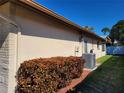 View of the home's side, highlighting the landscaping, clear skies, and central air conditioning at 2587 Blackwood Cir, Clearwater, FL 33763