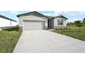 New construction home exterior with gray siding, stone accents, and a long driveway at 31703 Wild Grape Ln, Brooksville, FL 34602