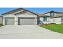 Two-car garage, light-grey exterior, and nicely landscaped front yard at 13851 Richland Gulf Cir, Parrish, FL 34219