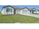 Light-colored house with gray accents, two-car garage, and a grassy lawn at 13859 Richland Gulf Cir, Parrish, FL 34219