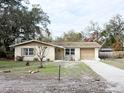 One-story house with a beige exterior, attached garage, and landscaping at 4935 Mockingbird Dr, Dade City, FL 33523