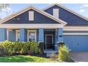 Two-story home with blue exterior, landscaping, and a dark brown door at 1570 Fox Grape Loop, Lutz, FL 33558