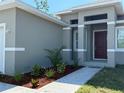 Close-up of the home's entryway, showing a modern, covered porch and a landscaped garden bed at 135 Sunset Rd, Rotonda West, FL 33947