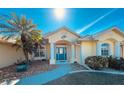 Front view of a house with a teal door and palm trees at 15392 Taurus Cir, Port Charlotte, FL 33981