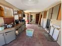 A galley-style kitchen with wood cabinets and red tile floors needs updating at 16211 3Rd E St, Redington Beach, FL 33708