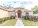 House exterior featuring a red front door, arched entryway, and neatly landscaped yard at 12908 Cattail Shore Ln, Riverview, FL 33579
