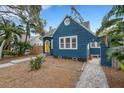 Quaint blue house with a yellow door and landscaped yard at 1143 13Th N St, St Petersburg, FL 33705