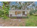 Quaint white cottage with a wooden porch and tree-lined yard at 7495 Mitchell Rd, Brooksville, FL 34601