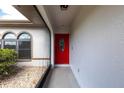 Stylish front entryway featuring a red, glass-paneled door and decorative stone landscaping at 1147 Yachtsman Ln, Punta Gorda, FL 33983