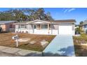 Newly renovated single-story home with a gray exterior, white garage door, and landscaped lawn at 6941 Twilite Dr, Port Richey, FL 34668