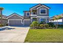 Beautiful two-story gray home with a three-car garage, stone accents, a well manicured lawn, and lush landscaping at 4606 Pond Brook Ct, Bradenton, FL 34211