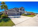 Two-story house with gray siding, stone accents, three-car garage, and landscaped yard at 4606 Pond Brook Ct, Bradenton, FL 34211