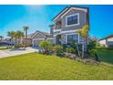 Beautiful two-story gray home with a three-car garage, stone accents, a well manicured lawn, and lush landscaping at 4606 Pond Brook Ct, Bradenton, FL 34211