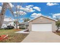 Tan house with white garage door, landscaped yard, and walkway at 6201 Cedarbrook N Dr, Pinellas Park, FL 33782