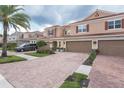 Townhome with a gray vehicle parked in the driveway, a neatly landscaped yard and paver driveway at 8726 Terracina Lake Dr, Tampa, FL 33625