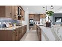 Modern kitchen with wood cabinets, marble countertops, and stainless steel appliances at 14517 Coastal Woodland Ln, Parrish, FL 34219
