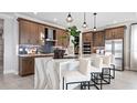 Modern kitchen with an island, wood cabinets, and marble countertops at 14517 Coastal Woodland Ln, Parrish, FL 34219