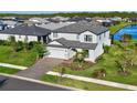 Two-story house with gray roof, paver driveway, and a view of a lake at 2546 Buckthorn Loop, North Port, FL 34289