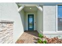 Modern teal front door entry with a stone accent wall and paver walkway at 2546 Buckthorn Loop, North Port, FL 34289