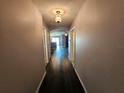 A view of the hallway with hardwood flooring and neutral walls leading to the living space at 2022 Peaceful Palm St, Ruskin, FL 33570