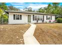 Newly renovated home with white exterior, landscaping, and walkway at 6154 Ashland Dr, Spring Hill, FL 34606