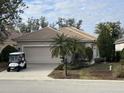 Tan single-story house with a two-car garage, golf cart, and palm trees at 3375 Osprey Ln, Port Charlotte, FL 33953