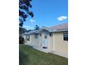 House exterior featuring a yellow-painted facade, white columns, and a lush lawn at 7580 Camminare Dr, Sarasota, FL 34238