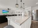 Modern kitchen island featuring a stainless steel faucet, white cabinets, and pendant lighting fixtures at 9189 Royal River Cir, Parrish, FL 34219