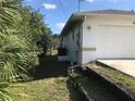 The side of the house with an AC unit, a garage, a partial fence, and some vegetation at 402 Lomond Dr, Port Charlotte, FL 33953