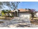 Inviting home exterior featuring a well-maintained lawn, blooming flowers, and an attached two-car garage at 12417 Adventure Dr, Riverview, FL 33579
