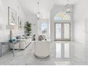 Bright foyer with soaring ceilings, marble floors, modern lighting, and a decorative glass front door at 6354 Cocoa Ln, Apollo Beach, FL 33572