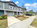 Charming townhome exterior with gray siding, a one-car garage, a well-manicured lawn, and a tidy garden at 2764 Emory Sound Pl, Brandon, FL 33510