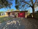 Single story home featuring a red garage door, a gravel driveway, and partial fencing at 3923 W Bay View Ave, Tampa, FL 33611