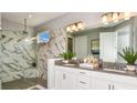 Elegant bathroom boasting a walk-in shower with marble-style tiling and dual vanity sinks at 4488 Isonzo Way, Wesley Chapel, FL 33543