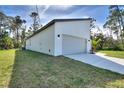 A view of the home's side exterior, showcasing its clean lines, two-car garage, and well-maintained lawn at 4044 Simkins Ave, North Port, FL 34286