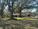 Home exterior featuring a large yard, a chain-link fence surrounding the property at 7306 Jones Rd, Odessa, FL 33556