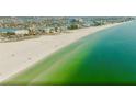 Panoramic aerial view of a pristine beach with white sand meeting the clear turquoise ocean water at 10111 Yacht Club Dr, Treasure Island, FL 33706
