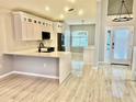 Bright kitchen featuring white cabinets, modern appliances, pendant lighting, and wood-look tile floors at 8283 47Th Street E Cir, Palmetto, FL 34221