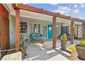 Inviting front porch with stone flooring, seating, potted plants, and a decorative pergola at 1321 Groveland Ave, Venice, FL 34285