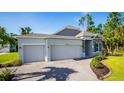 Charming home featuring a three-car garage, stone accents, and a well-maintained lawn at 25172 Calusa Dr, Punta Gorda, FL 33955