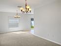 Open living area with neutral carpet and lots of natural light, accentuated by elegant chandeliers at 2313 Richwood Pike Dr, Ruskin, FL 33570