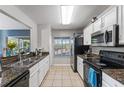 Efficient kitchen layout with white cabinets, modern appliances, and tiled flooring creates a clean and functional space at 10759 Keys Gate Dr, Riverview, FL 33579