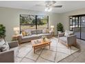 Bright living room with large picture window, ceiling fan, neutral paint, stylish furnishings, and a cozy area rug at 8379 Begonia St, Spring Hill, FL 34608