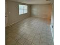 Empty living room featuring neutral walls, tile flooring, a large window, and access to other rooms at 4325 Newbury Dr, New Port Richey, FL 34652