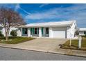 Front view of a single-story home with a white exterior, teal shutters, and a two-car garage at 9205 40Th N Way # 5, Pinellas Park, FL 33782