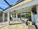 This covered patio features brick pavers, a ceiling fan, and overlooks the screen enclosed pool and backyard at 1280 Windy Bay Shl, Tarpon Springs, FL 34689