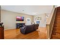 Cozy living room featuring hardwood floors, staircase, and a large tv at 5808 Falconcreek Pl, Lithia, FL 33547